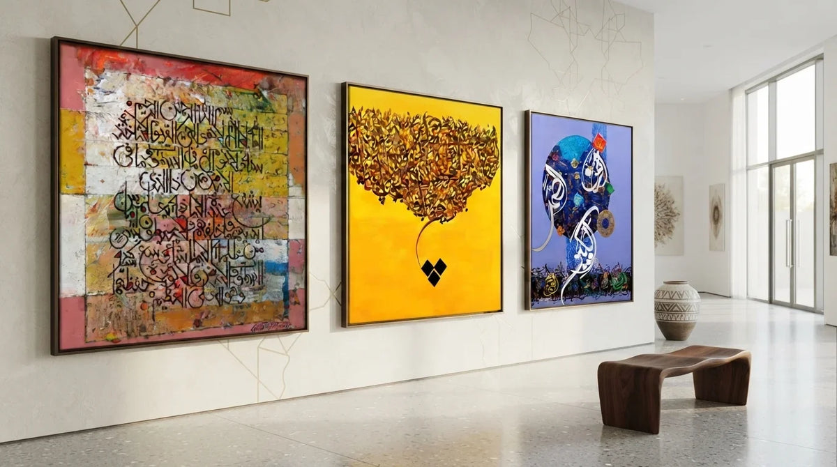 Three framed abstract artworks, including islamic art calligraphy, hang on a white gallery wall beside a wooden bench and a decorative vase near tall windows.